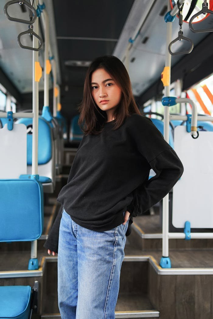 Stylish young woman posing confidently inside a modern bus, showcasing travel fashion and style.